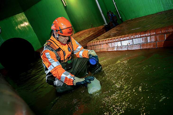 Dieses Bild zeigt einen Mitarbeiter Stadtentwässerung bei einer Probenahme aus dem Kanal.