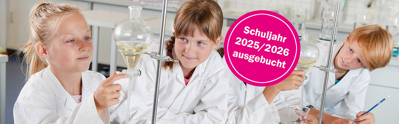Drei Kinder in weißen Kitteln experimentieren im Schülerlabor