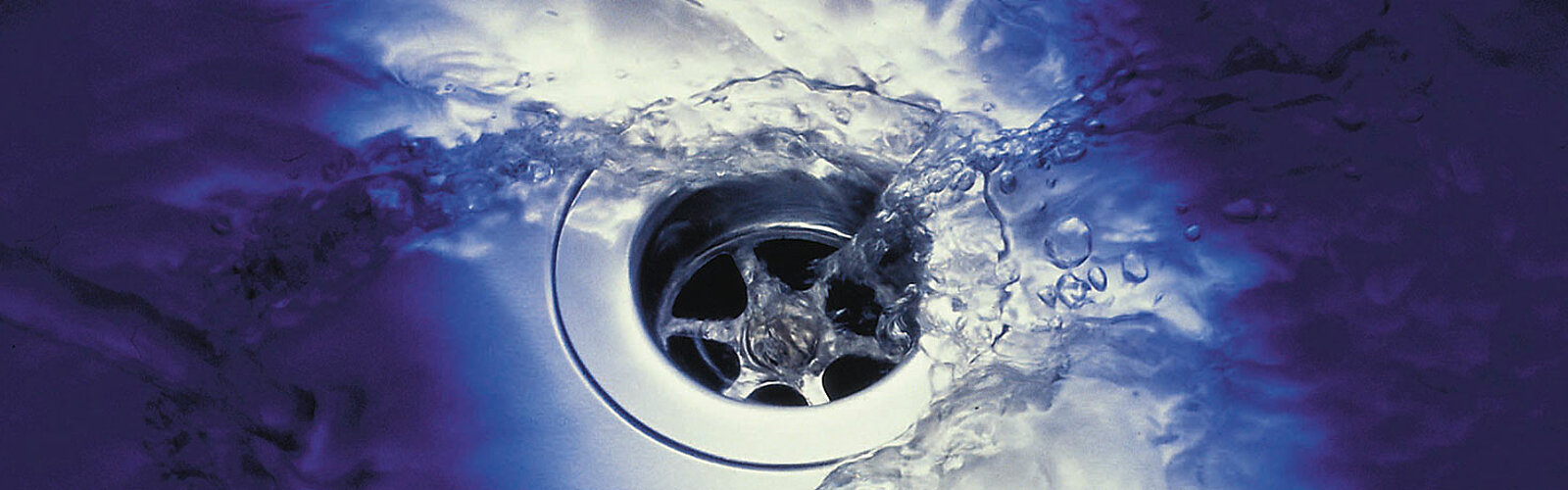 Das Bild zeigt den Abfluss einer Spüle, in den Wasser fließt.