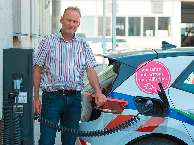 Ein Mann lehnt an einem mit Strom betriebenen Auto.